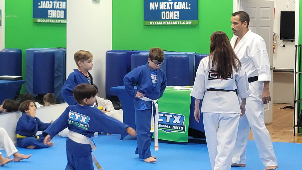 Child repeating a karate technique as instructors give feedback