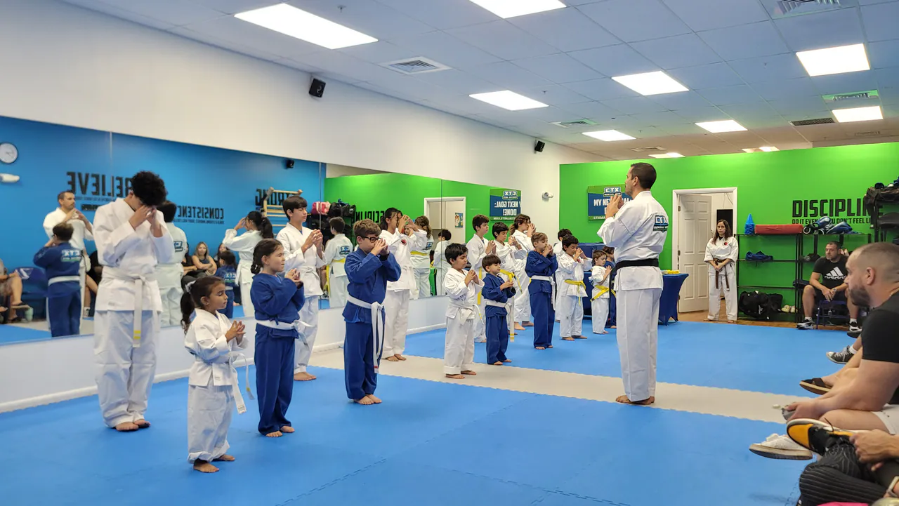 Kids in white and blue uniforms during a karate class as parents watch from the side