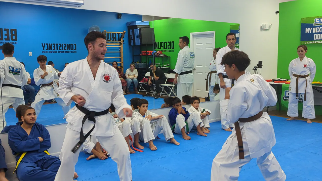 Karate instructor working with a student while classmates sit and watch