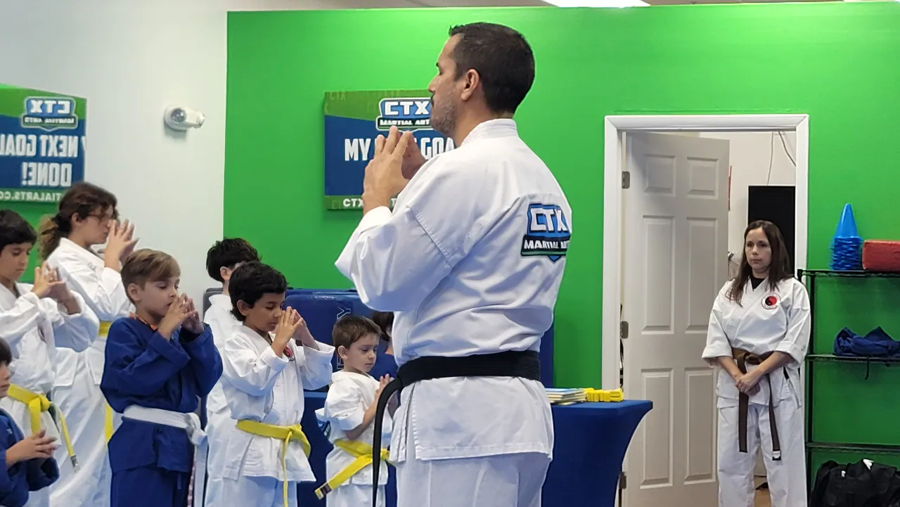 Black belt instructor bowing in front of a line of kids in karate uniforms at CTX Martial Arts in Kendall