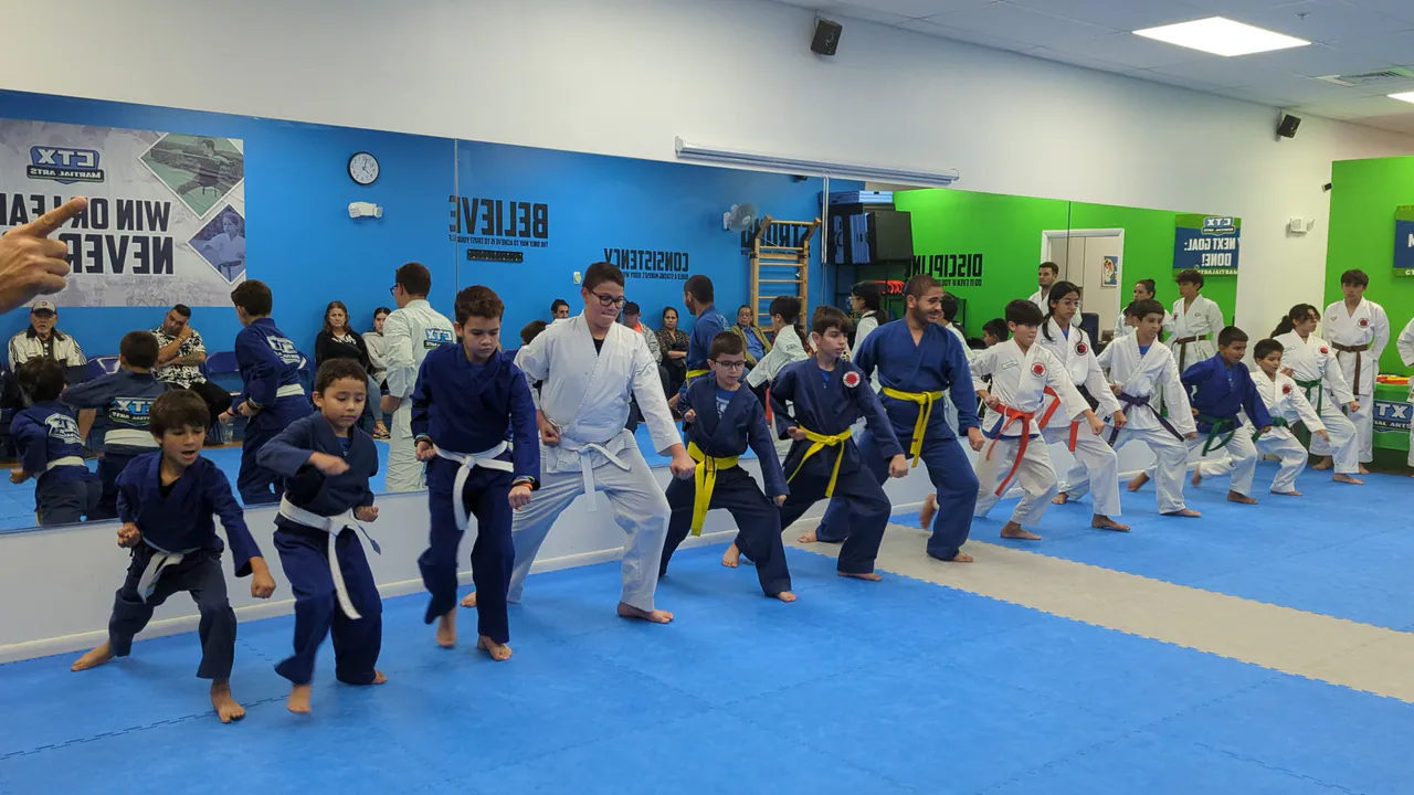 Kids practicing karate in rows with close instructor supervision