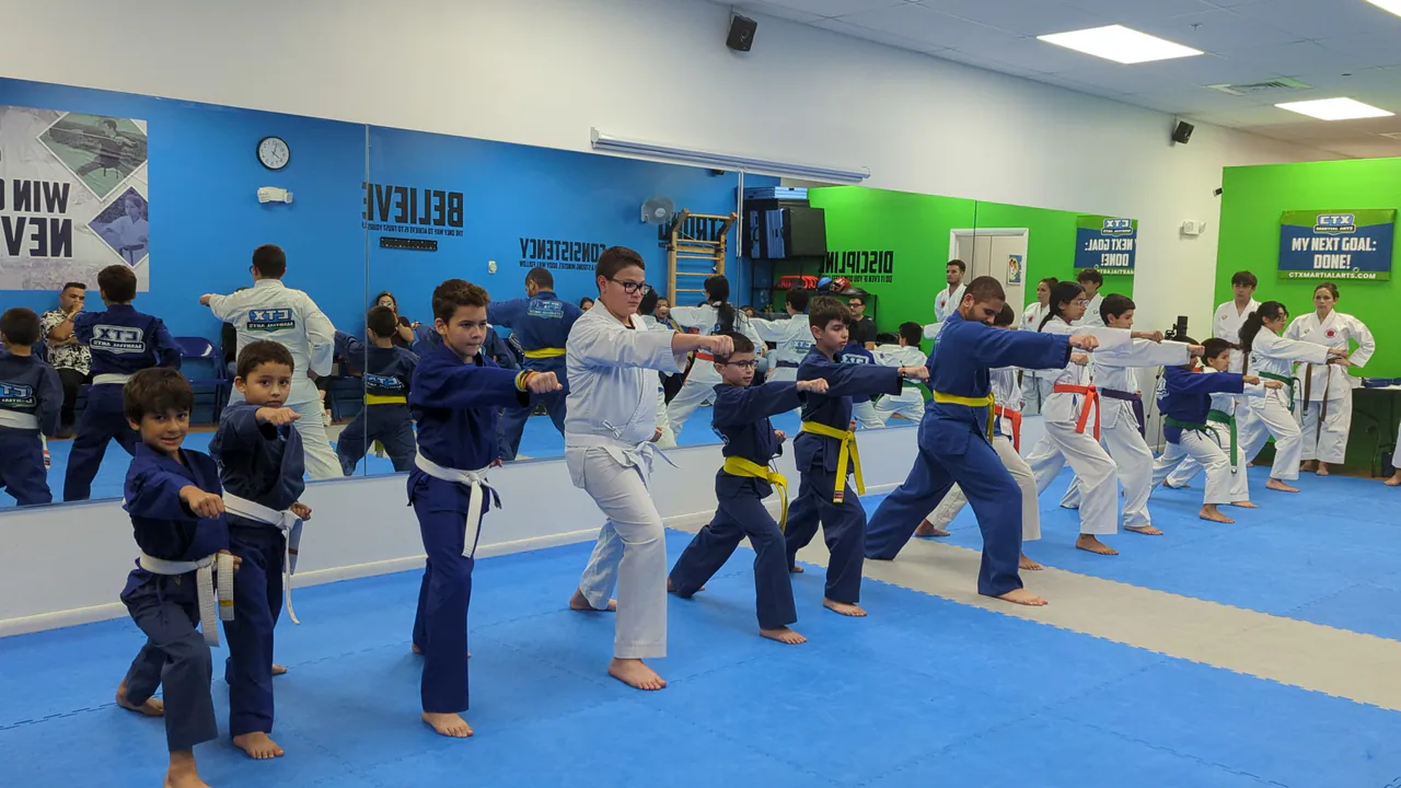 Kids in blue uniforms practicing karate punches in a calm, organized line