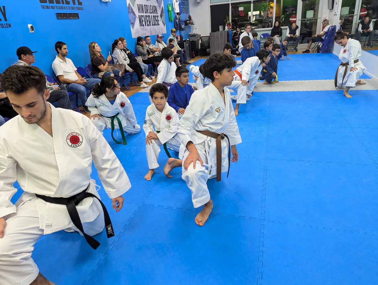 Kids practicing karate fundamentals in a low stance alongside an instructor