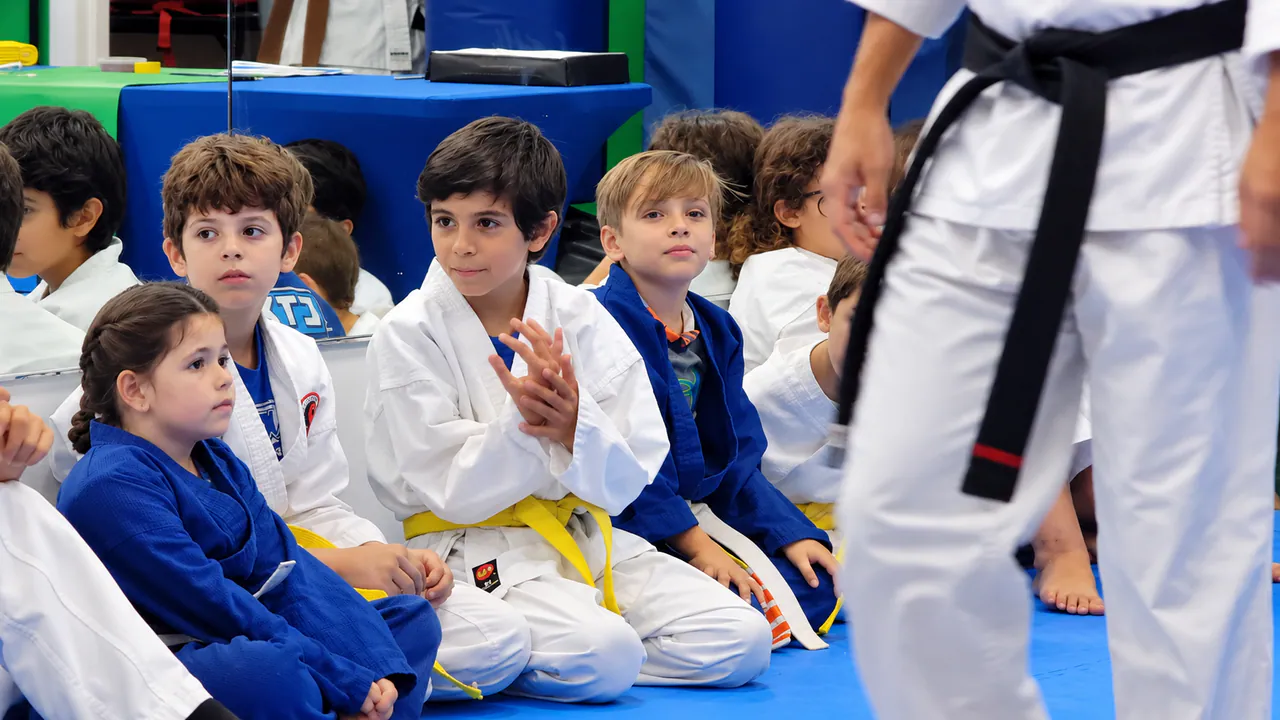 New young students sitting on the mat watching a karate demonstration