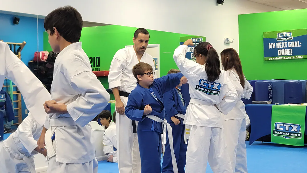 Instructor adjusting a young student's karate technique one on one