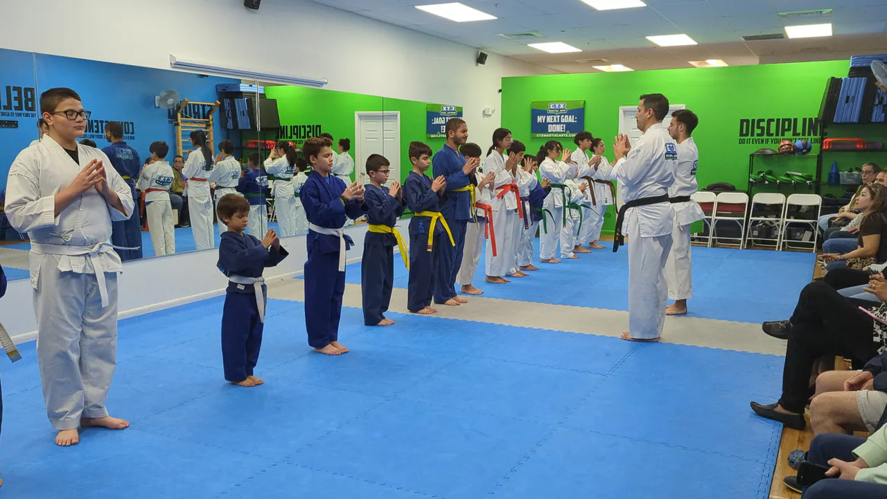 Parents watching from chairs as a kids beginner karate class lines up on the mat