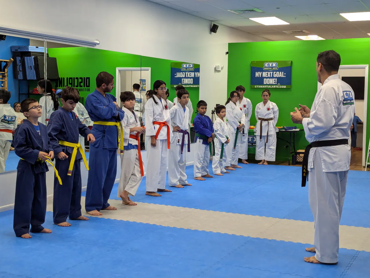 Sensei leading a youth karate class lined up by belt color