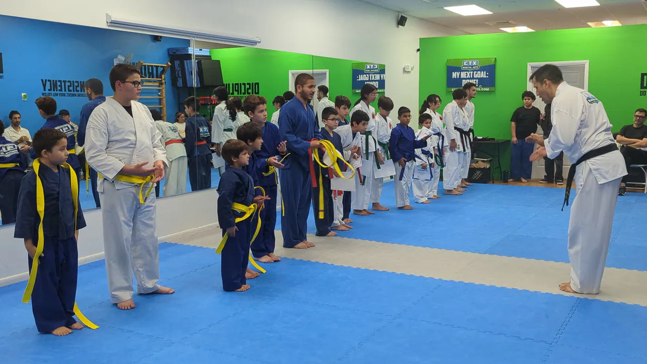 Sensei teaching a youth karate group standing in rows by belt color